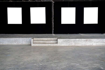 Four white picture frames were hung in a gallery on a black fabric wall.の写真素材