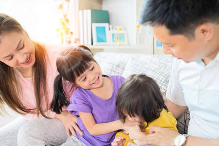 Happy Asian family playing together at sofa in home living room, the image of a happy Asian family laughing on couchの写真素材