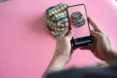 Men take photos of hats with their mobile phones or digital cameras on smartphones to post for sale online on the Internet.の写真素材