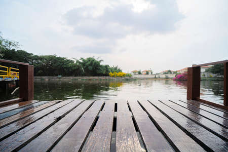 Lake pier at evening with hills on background. Reflection of the forest in the green water with blue cloudy sky. Small lakeの写真素材