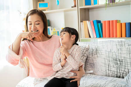 Mother teaches her child daughter accurately brushing teethの写真素材