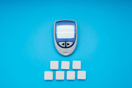 Sugar cubes and Glucose meter on blue background, world diabetes day. Copy space. Top viewの写真素材