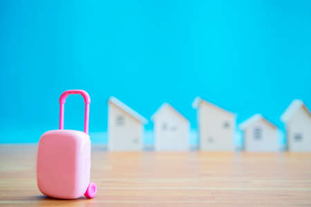 Small pink suitcase with tiny wooden house Holiday rentals ideas for renting homes and private rooms.の写真素材