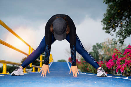 Fitness woman doing exercises of the lungs to train the leg muscles. The active woman stood up to the blue and bent her hands on the floor to loosen her muscles.の写真素材