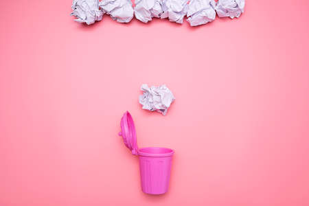The crumpled paper is falling into the pink bin, lying on a pink background.の写真素材