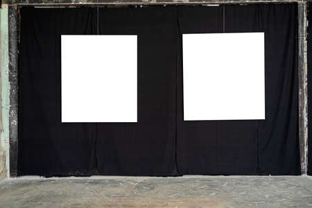 Two white picture frames were hung in a gallery on a black fabric wall.の写真素材