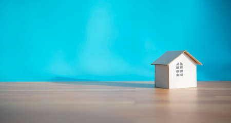 White paper house design isolated on blue background, shadows showing warmthの写真素材