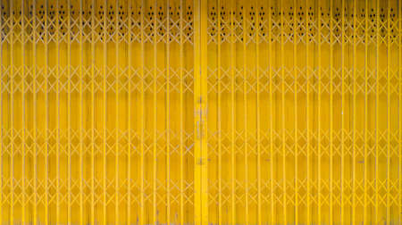 Old vintage iron yellow doors. Steel folding gates. Selective focus.の写真素材