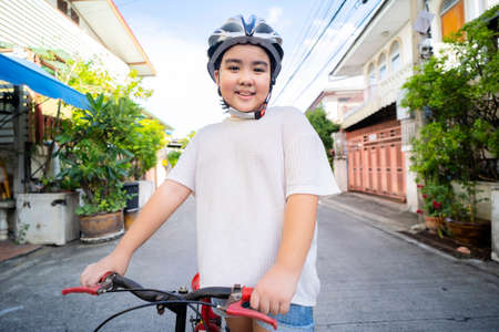 A cute girl begins to learn to ride a bicycle in the village where she lives. Equipped with a helmetの写真素材