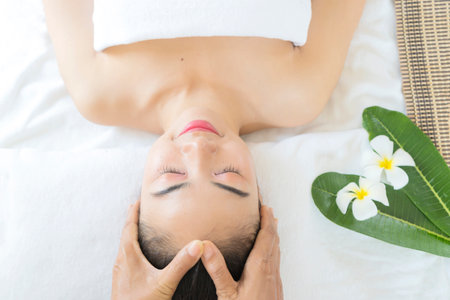 Beautician massaging woman's face. Attractive girl having facial treatment and massage. The young woman is lying and relaxingin.の写真素材