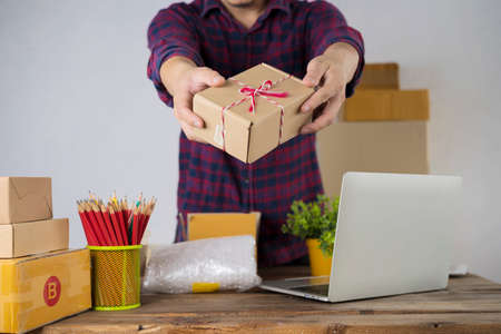 Laptop computer at workplace of start up, small business owner. cardboard parcel box of product for deliver to customer. Online selling, e-commerce, packing concept,work from homeの写真素材