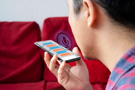 Chatbot assistant conversation, Ai Artificial Intelligence technology concept. Casual business man chatting with chatbot via mobile smart phone application while workingの写真素材