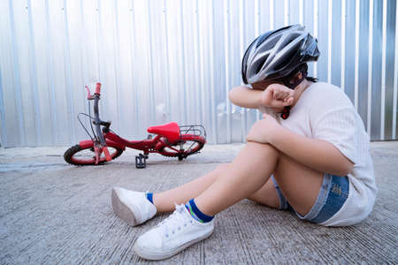 Child who was involved in a falling bicycle accident. Little girl shows mother wound on elbow after...
