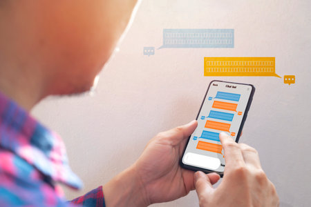 Chatbot assistant conversation, Ai Artificial Intelligence technology concept. Casual business man chatting with chatbot via mobile smart phone application while workingの写真素材
