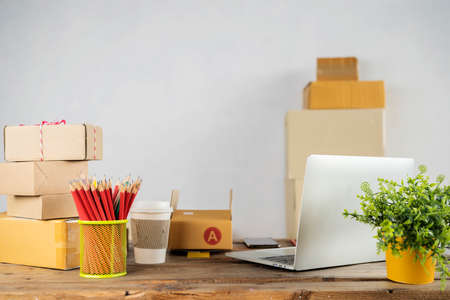 Laptop computer at workplace of start up, small business owner. cardboard parcel box of product for deliver to customer. Online selling, e-commerce, packing conceptの写真素材