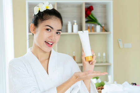 Happy attractive young woman hold creme jar look at camera, smiling lady in bathroom, facial skin care treatment, skincare concept, close up portraitの写真素材