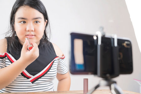Portrait of young asian woman review giveaway gift product fan following channel, recording video make up lipstic cosmetic at home. Online influencer girl social media marketing live steaming conceptの写真素材