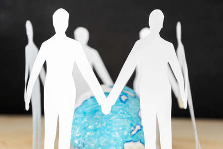 Paper people standing in circle around globe, people connected to each otherの写真素材