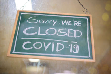 Temporarily closed sign for Covid-19 in small business activity. Information notice sign about quarantine measures. Close up on a red closed placard in the window of a shop for coronavirus.の写真素材