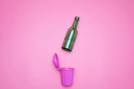 Top view of green glass bottle trash and waste isolated from pink recycle idea.