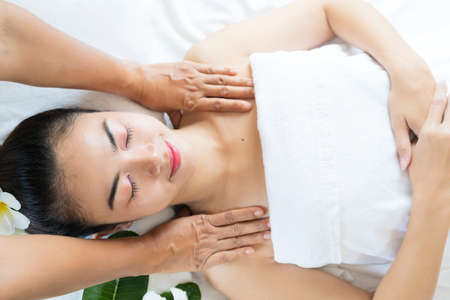 Beautiful young woman receiving massage in spa salon. Hands of a masseur massaging back of a young adult woman in spa salonの写真素材