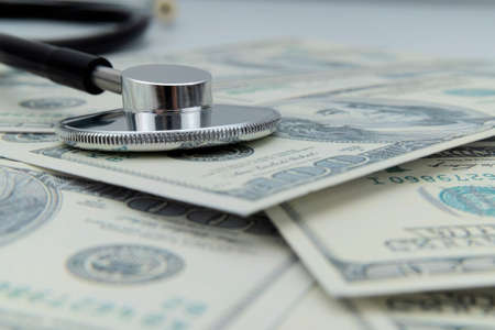 Close-up of a stethoscope on dollar bills, heap of dollars with stethoscopeの写真素材