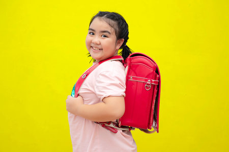 Cute female students and carrying a school bag Ice cream isolated on yellow background. Back to school concept.の写真素材