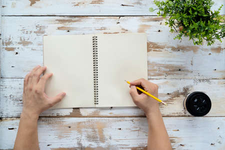 man hands writing on book in office. Business man working on desk of wood and office supplies on top view.Copy space.の写真素材