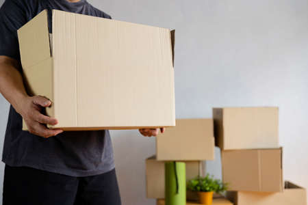 House moving concept. Man holding cardboard box, closeup. Moving boxes in new apartment, real estateの写真素材