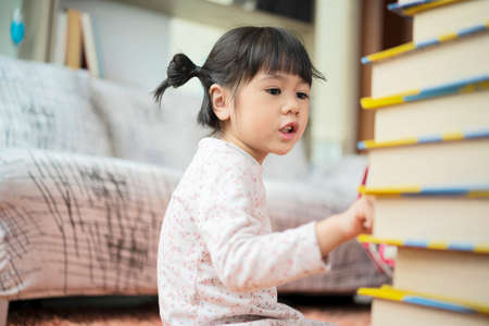 Education and school ideas - Little girl students are studying at school. I am practicing counting from the number of books available.の写真素材