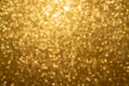 Gold Festive Christmas background. Abstract twinkled bright background with bokeh defocused golden lightsの写真素材