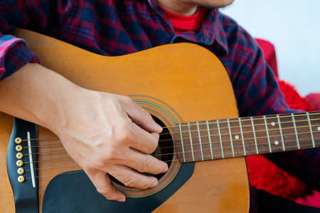 Close up of man hand playing guitar, person playing an acoustic guitar.の写真素材