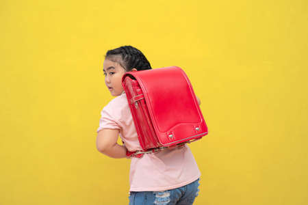 Cute female students and carrying a school bag Ice cream isolated on yellow background. Back to school concept.の写真素材