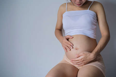 Happy pregnant woman touching her beautiful belly. Pregnancy, motherhood, and expectationの写真素材