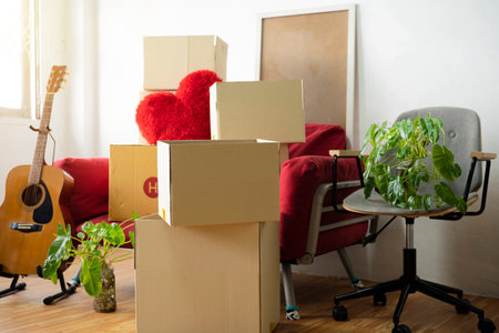 Moving day concept, cardboard carton boxes stack with household belongings in modern house living room, packed containers on floor in new home, relocation, renovation, removals and delivery serviceの写真素材