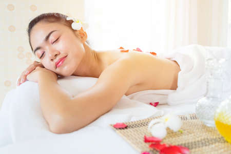 Young woman brunette skin relaxing in spa salon lie on your stomach, opened eyes and smilingの写真素材