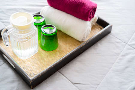 Set of hotel amenities (such as towels, drinking glass etc) on the bed. Hotel amenities is something of a premium nature provided in addition to the room when renting a room.の写真素材