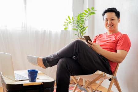 Handsome man using laptop computer at home. Student men resting in his room. Online shopping, home work, freelance, online learning, studying concept. Distance educationの写真素材