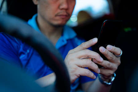 Man inside a car hand holding mobile phone with map gps navigation. Driver searching location via locator navigator application via smartphone before driving a car, close upの写真素材