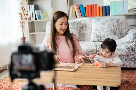 Mother and her daughter preparing natural mask with cream and honey and record video for on line blogの写真素材
