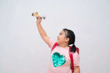 Cute little girl playing with a toy airplane. Low angle view of pretty 9 year old Hispanic girl playing with toy model airplaneの写真素材