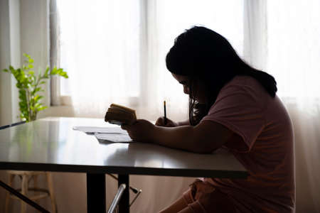 Girl doing homework, a funny child girl doing homework writing and reading at home