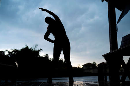 Young beautiful Asian woman in sports outfits doing stretching before workout outdoor in the park in...