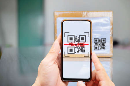 Two hands holding a mobile phone scanning a QR code. Modern stylish mobile phone scanning QR code on...