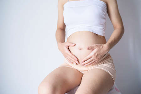 Pensive pregnant woman dreaming about child. Young happy expectant thinking about her baby and enjoying her future life. Motherhood, pregnancy, happiness concept, copy spaceの写真素材