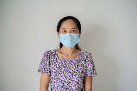Portrait of a young girl in a medical mask isolated on a white wall background. Young woman patient, copy spaceの写真素材