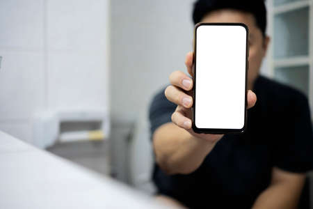 Smart phone with white screen background in toilet, restroom or WC. Closeup of hands using mobile phone with blank copy space screen, empty white screen for advertising text in toilet, restroom or WCの写真素材