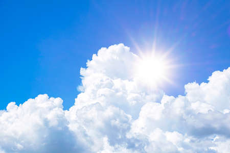 The sky is full of clouds floating around , both small and large, the sun is shining brightly.の写真素材