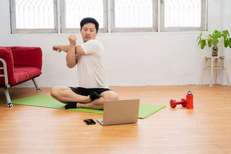 Online workout. Young man doing plank exercise with online tutorial at home, free spaceの写真素材
