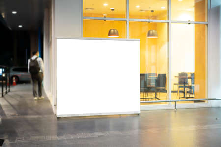 mockup white poster with black frame stand in front of blur restaurant cafe background for show or...